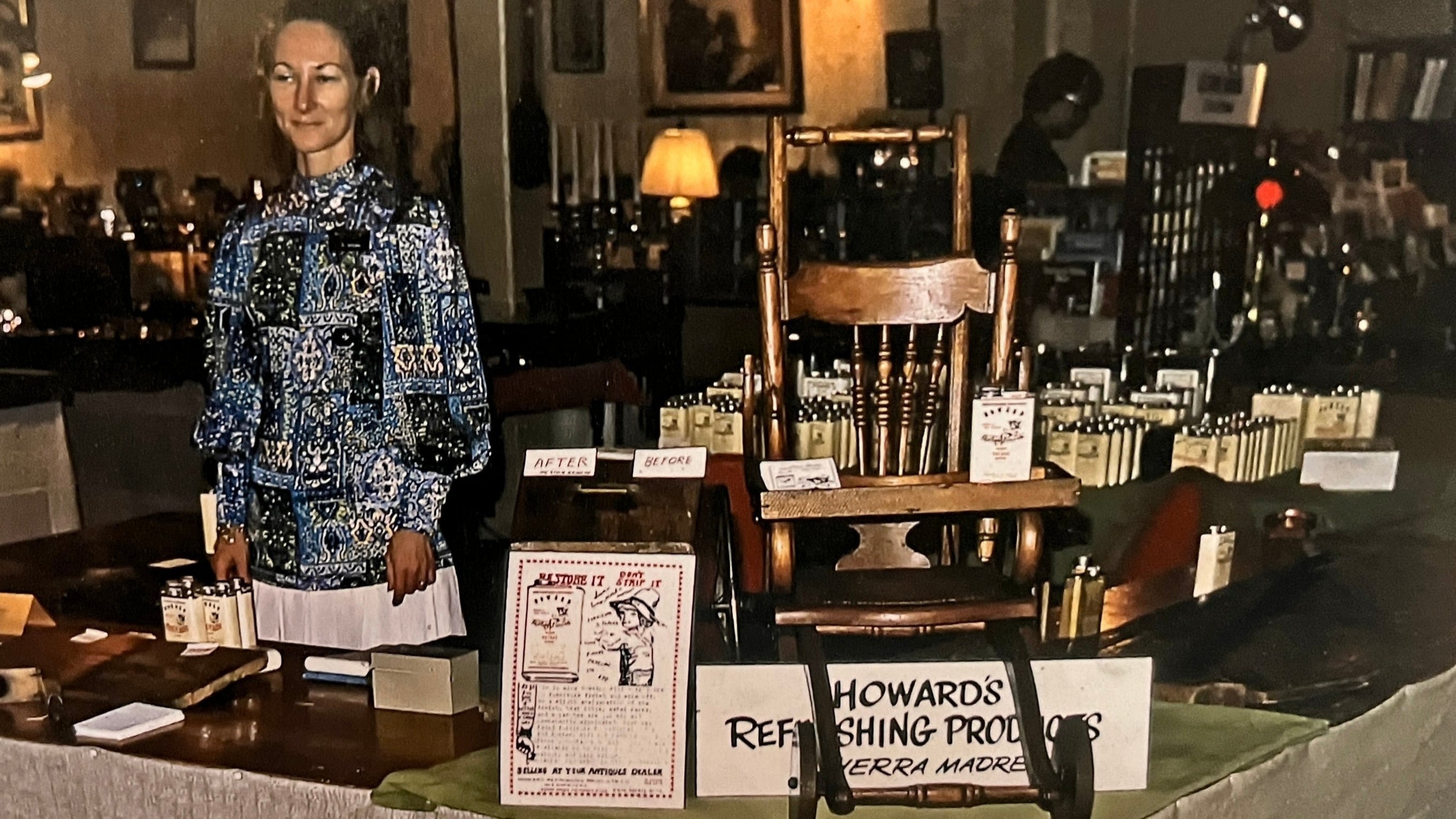 Woman standing next to a display of vintage furniture and products in a store setting.